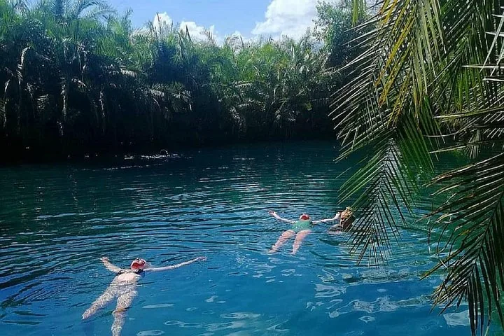 Deux personnes flottant sur le dos dans un bassin naturel d'eau bleue paisible.