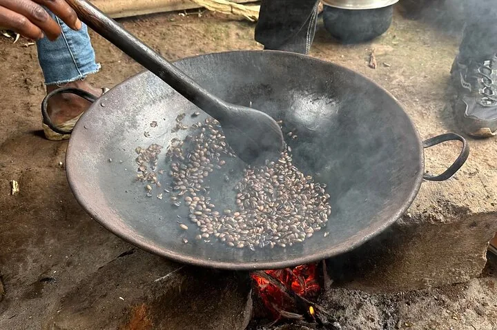 Torréfaction des grains de café dans une grande poêle en métal sur un feu de bois.